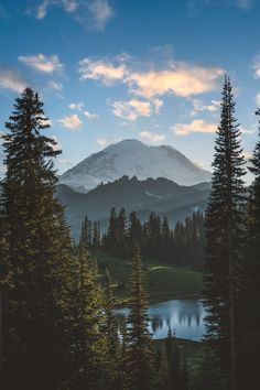 the sun is setting on a mountain with trees and water in front of it,