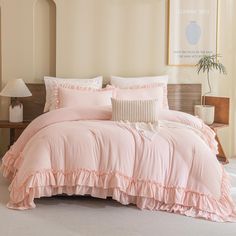 a bed with pink ruffled sheets and pillows