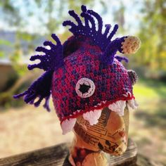 a crocheted hat is sitting on top of a wooden table outside in the sun