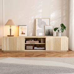 a living room with an entertainment center, lamp and pictures on the wall above it