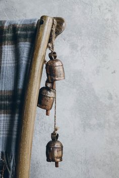 three bells hanging from a wooden pole next to a plaid thrower on a wall