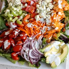 a salad with tomatoes, lettuce, carrots and other toppings on it