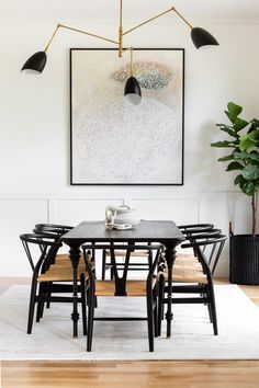 a dining room table with four chairs and a large painting on the wall above it