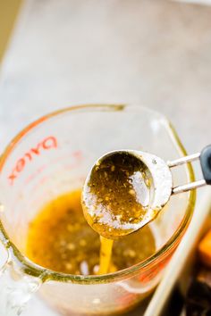 a glass measuring cup filled with liquid next to carrots