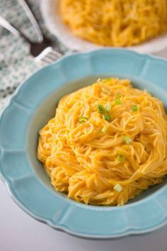 a plate of spaghetti and potatoes on a white table with two plates in the background