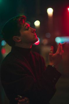 a man standing on the street holding his hand up to something in front of him