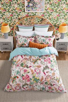 a bedroom with floral wallpaper and colorful bedding