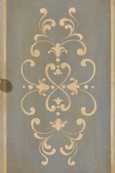 an ornate design is painted on the side of a wall in grey and beige colors