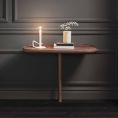 a table with a candle and some books on it in front of a gray wall