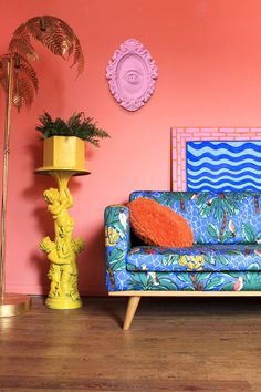 a blue couch sitting next to a yellow vase on top of a hard wood floor