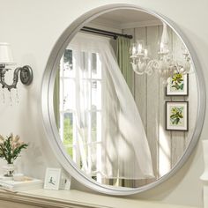 a large round mirror sitting on top of a mantle next to a lamp and window