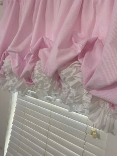 pink and white ruffled curtains hanging from a window