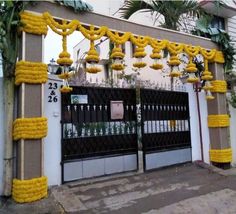 a gate decorated with yellow flowers and hanging from it's sides in front of a building