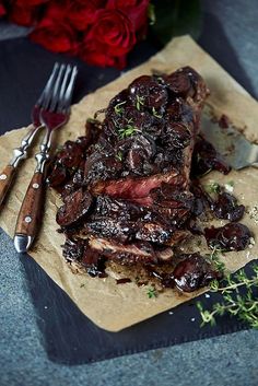 a piece of meat sitting on top of a cutting board next to a knife and fork