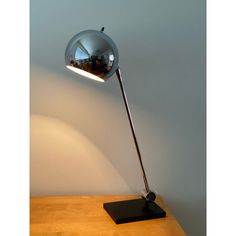 a lamp that is sitting on top of a wooden table next to a white wall