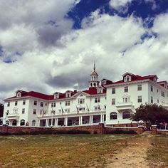 a large white building with a red roof and two stories on the top floor is surrounded by green grass