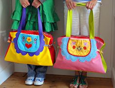 two children standing next to each other holding colorful handbages in front of their faces