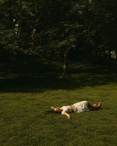 a person laying on the grass in front of trees