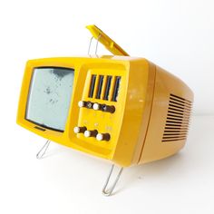 an old yellow television sitting on top of a white table