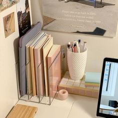 a computer monitor sitting on top of a desk next to a pile of books and papers