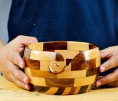 a person holding a wooden bowl on top of a table