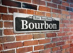 a sign on a brick wall that says rue bourbon