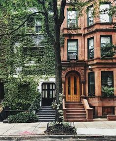 an old brownstone house with ivy growing on the side and stairs leading up to it