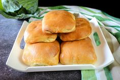 four rolls stacked on top of each other in a white plate with green napkins