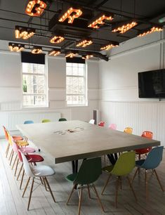 an empty conference room with many chairs and a large table in front of a flat screen tv