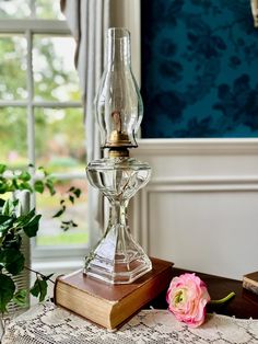 a glass candle holder sitting on top of a table next to a flower and books