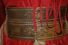 a close up of a metal belt on a person's waist with red ribbon