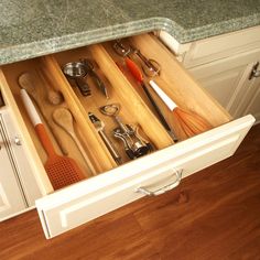 an open drawer in a kitchen filled with utensils and other kitchen items,