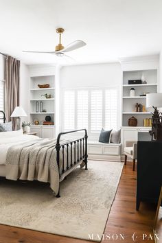 a bedroom with white walls and wood flooring has a large bed in the center