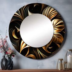 a round mirror sitting on top of a wooden shelf next to a vase with flowers