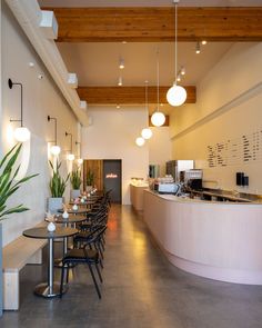 an empty restaurant with tables and chairs next to the counter area, along with potted plants