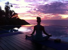 a woman sitting on the edge of a swimming pool at sunset