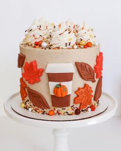 a frosted cake decorated with fall leaves and cupcakes