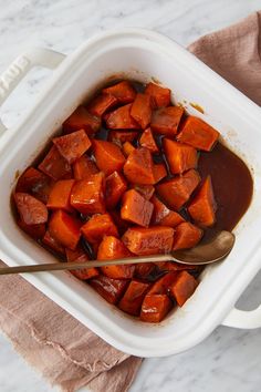 a white casserole dish filled with cooked carrots