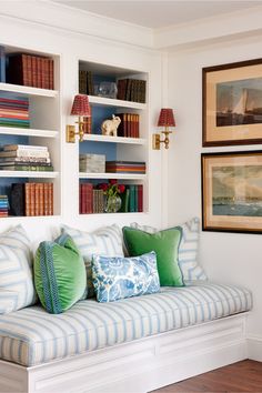 a striped couch with pillows on it in front of bookshelves filled with books