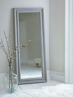 a large mirror sitting on top of a table next to a vase