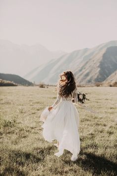 a woman in a dress is walking through the grass