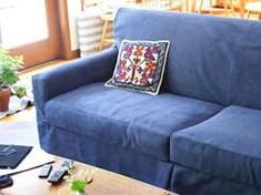 a blue couch sitting in front of a laptop computer on top of a wooden table