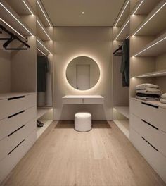 an empty walk in closet with white drawers and lights on the ceiling, along with a round mirror