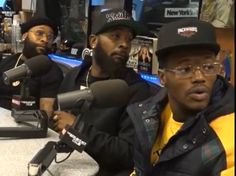 three black men sitting in front of microphones at a radio station, one is speaking