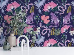 the wallpaper in this kitchen is colorful and has pink flowers, blue lizards, and green leaves