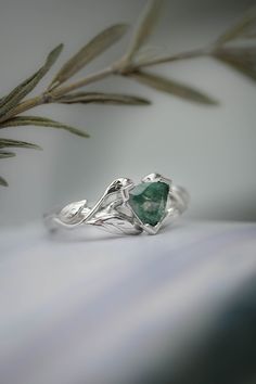 a close up view of a ring with a green stone in the center on a white surface