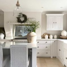 a kitchen with white cabinets and an island in front of the countertop, surrounded by wicker chairs