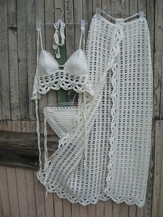 a white crochet bralet hanging on a wooden wall next to an umbrella