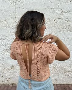 a woman standing in front of a white wall with her back turned to the camera