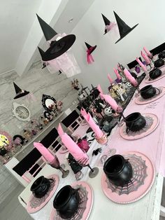 the table is set with black and pink decorations for halloween dinnerware, including witches hats